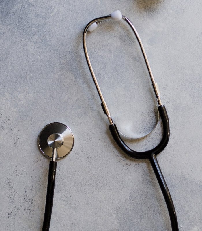 Black and Silver Medical Stethoscope Lying on Smooth Light Gray Background Surface
